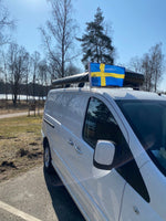 Svensk bilflagga monterad på taket av en vit bil, perfekt för camping och resor i Sverige.