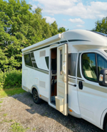 Husbil parkerad på stallplats med öppen dörr – dörrhållare tillbehör för husbil och husvagn