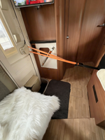 Dörrsäkring i orange spänd över dörröppning i husbilsinteriör – skyddar mot inbrott vid camping