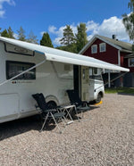 Husbil med utfälld markis parkerad på grusuppfart – Smart Camping tillbehör för husbil och husvagn
