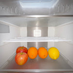 Insida av kylskåp med äpplen, apelsiner och citron på hylla – smart matförvaring i husbil och camping