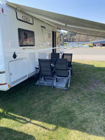 LMC husbil med utfälld markis och campingstolar på grön gräsmatta vid camping.