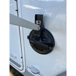 Svart sugkoppsbaserad markishållare monterad på sidan av en vit husbil, håller markisarmen på plats.