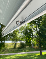 Krok med ögla i metall monterad i markisspår på husbil, för upphängning av tillbehör.