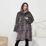 Dam i grå oversized hoodie-filt framför soffa, modellbild – camping.
