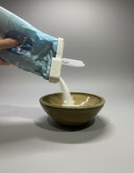 Påsklämma monterad på blå påse – häller innehåll i keramikskål, praktisk kökstillbehör för husbil och camping