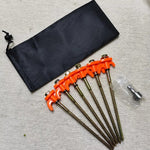 Sex orangefärgade tältpinnar med svart förvaringspåse – stabila markankar för tält och camping.